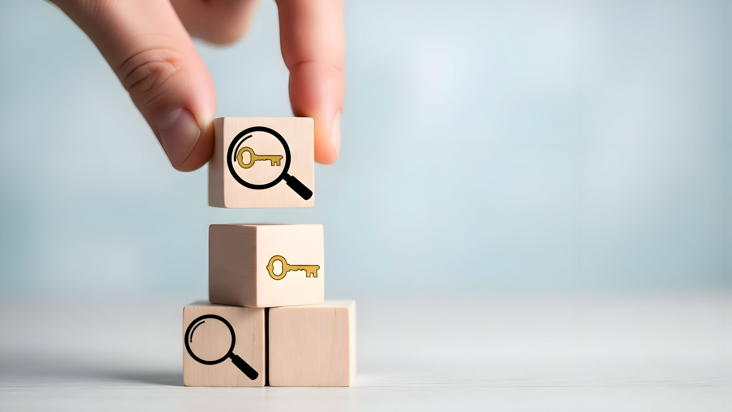 A hand stacking wooden blocks, each featuring icons—a magnifying glass, a key, and a magnifying glass with a key inside—symbolizes search, discovery, and solutions in local SEO.